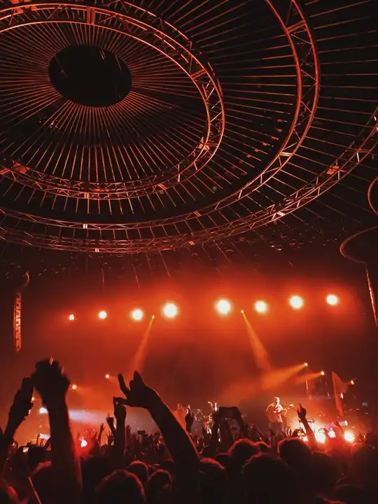 Foule enthousiaste levant les bras devant une scène illuminée lors d'un concert live