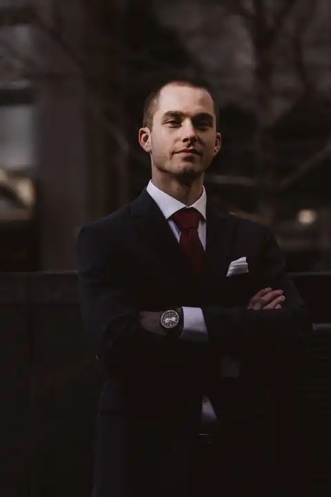 Portrait d'un homme en costume noir avec cravate rouge, posant avec assurance