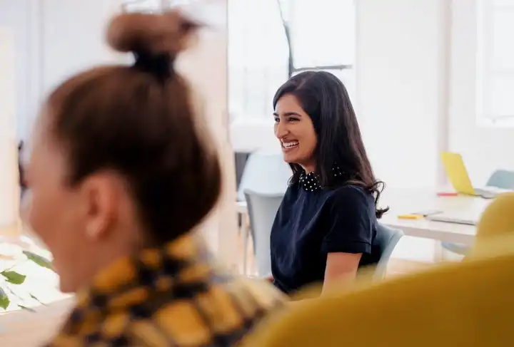Femme souriante en discussion dans un espace de coworking lumineux