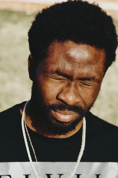 Portrait d'un homme barbu fermant les yeux sous une forte lumière naturelle